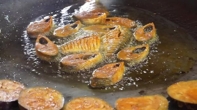 Hilsha fish is fried in a big pan along with shrimp and eggplant, Hilsha Fish and shrimp Simmering in mustard oil, traditional Bengali style fried hilsa and eggplant