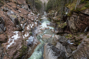 Obraz premium Flume Gorge in New Hampshire is a scenic chasm with rushing water and rugged granite. A popular hiking spot with trails and wooden walkways, it offers stunning views amid snow and moss-covered rocks