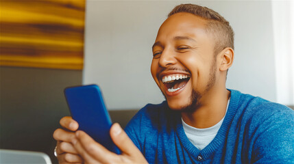 Cheerful man laughing while using smartphone, sitting in modern casual setting. Concept of social media, digital entertainment and positive communication.