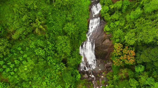 A tropical waterfall in a mountain canyon surrounded by jungle. Kuda Falls, Sri Lanka.