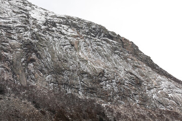 Snow-covered granite cliffs in the White Mountains of New Hampshire. The rugged rock face features dramatic textures, showcasing the region’s natural beauty and appeal for hikers and climbers