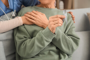 Nurse hugging mature woman after chemotherapy on sofa at home, closeup. Brain cancer concept