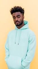 Obraz premium Stylish Man in Mint Hoodie Against Soft Yellow Tones