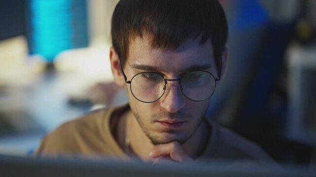 AI developer with glasses analyzing algorithms and data networks at a nighttime workplace for tech solutions.