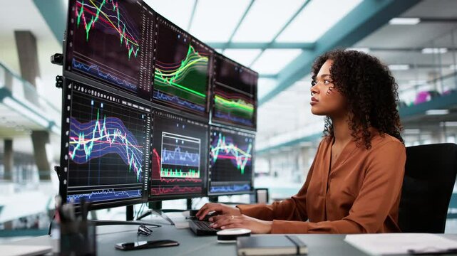 Stock Market Broker Looking At Graphs On Multiple Screens
