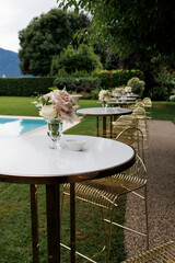 modern classic floral wedding decoration with lots of roses on the tables with wooden chairs in Italian villa, destination wedding 