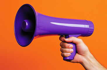 Une main d'homme tenant un m&eacute;gaphone violet sur fond orange