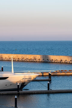 Luxury yacht docked at marina with sunset reflection, Barcelona, Spain.