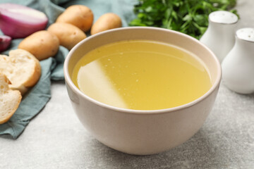 Tasty chicken bouillon in bowl on grey table, closeup