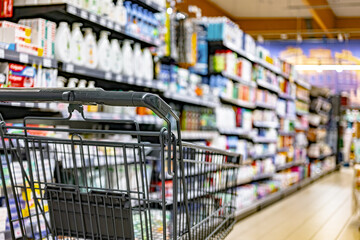 A shopping cart by a store shelf in a supermarket © monticellllo