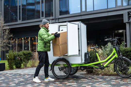 Bicycle courier delivering parcels on a cargo bike in the city
