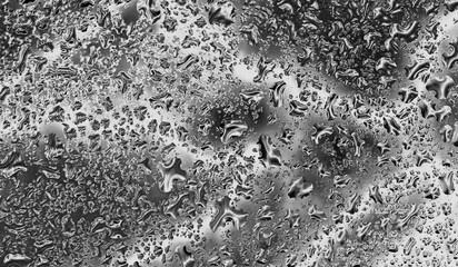 Close-up of black and white water droplets on glass, creating a dramatic and moody abstract pattern. Template for backgrounds, textures, and artistic designs. Abstract background.