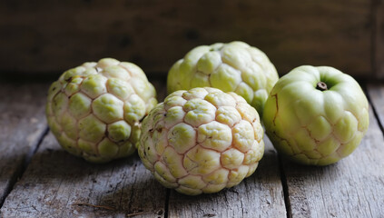 Obraz premium Fresh custard apples on rustic wooden surface, showcasing their unique texture and color
