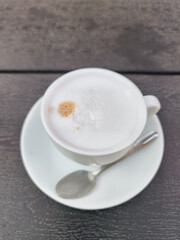 Creamy cappuccino resting on dark wooden table in prague