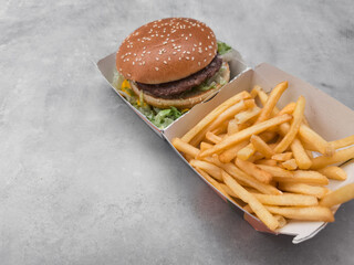 Hamburger and french fries served in cardboard container on gray background galentines day