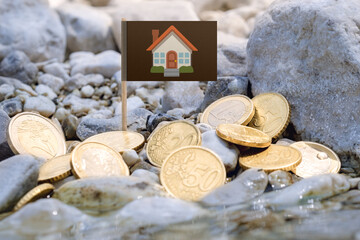 house flag with euro currency coins amid gravel surface and flowing water on the riverbank.Rent,mortgage,business concept.Macro close-up.