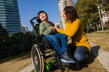 Mother playing with son in wheelchair in city park
