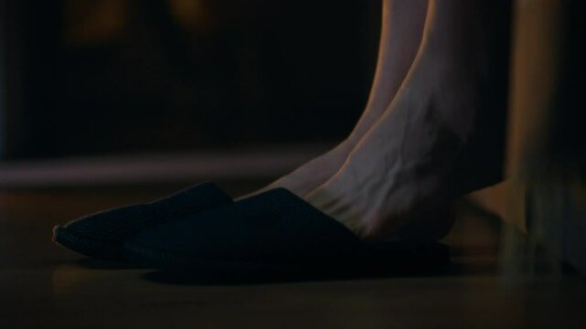 A young man at night got out of bed put on room slippers and went the kitchen. Close-up of the legs of guy who put on slippers went to the toilet at night. The concept of everyday life of young people
