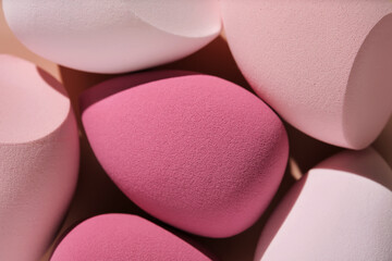 A set of makeup sponges on a pink background.