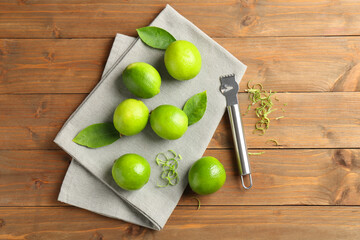 Lime zest, zester, leaves and fresh fruits on wooden table, flat lay