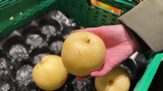 Customer choosing fresh asian pears at the supermarket