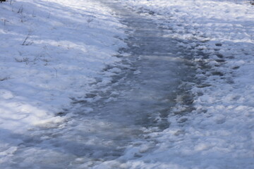 A stream runs through a snowy field with winter scenery, suitable for use in winter-themed presentations and designs.