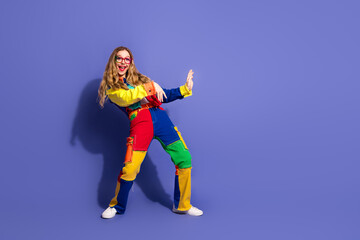 Fashionable young woman posing in a colorful outfit against a violet background, showcasing cheerful expressions and stylish gestures