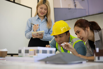 Fototapeta premium Three people are working together on a project, with one man wearing a yellow hard hat. They are all focused on the task at hand, and it seems like they are collaborating to create something 