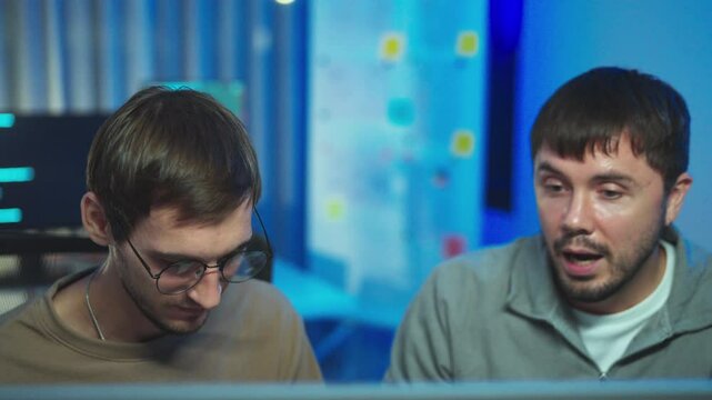 Coder and computer programmers, They discuss coding projects, focused in a vibrant, neon-lit workspace.