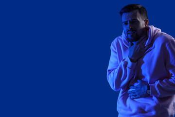 Young man having panic attack on blue background