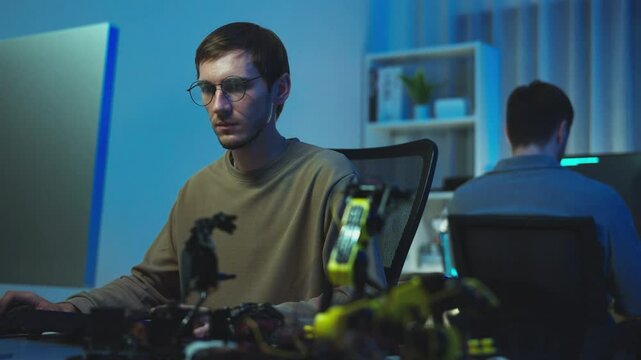 Watch a team of programmers brainstorm strategies for intelligent software in a modern office at night.