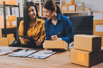Asian SME business women use laptop computer checking customer order online shipping boxes at home....