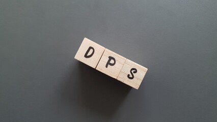 DPS acronym made of wooden letter cubes on dark background. Dividends Per Share