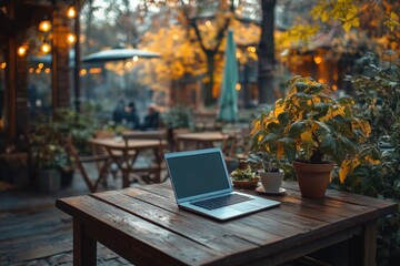 Fototapeta premium A laptop rests on a wooden table surrounded by plants in a peaceful outdoor cafe during autumn. Generative AI