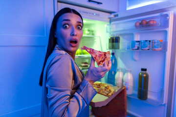 Afraid woman caught in the act of eating slice of pizza, having unhealthy snack late at night,...