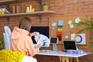Female fashion designer working with color palettes at table in office