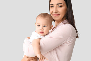 Happy mother with her little baby on light background, closeup