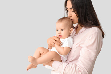 Happy mother with her little baby on light background