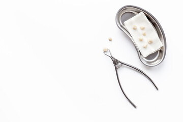 Dentist are holding bowl with dental teeth crowns for dental prosthetics, top view. Dentist desk, white background