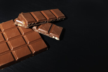 chocolate bar on black background. milk chocolate on black stone