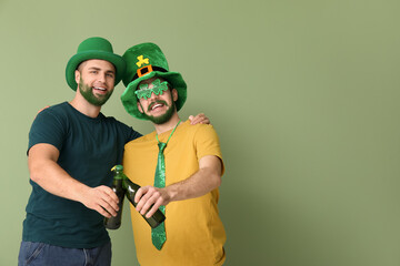 Young men in leprechaun hats with green beards holding bottles of beer on green background. St....