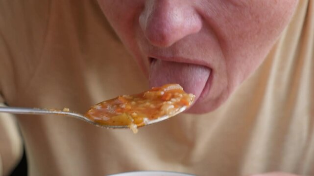 Woman eating kharcho soup with spoon close-up.
