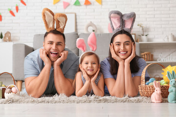 Happy family in bunny ears with Easter gifts lying on floor at home