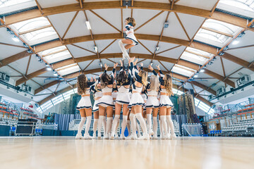 Cheerleaders Performing Dance Routine in Modern Sports Arena with Enthusiastic Spirit. High quality...