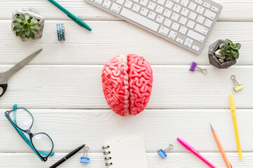 Human brain model on an office table with stationery and a keyboard, top view. Creative brain and business idea concept