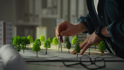 A designer is meticulously working on a scale model featuring green trees and urban buildings - Powered by Adobe