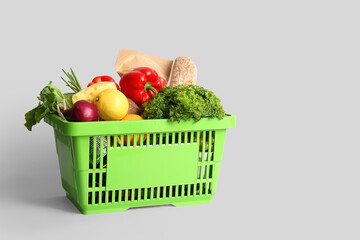 Green shopping basket full of different fresh products and bell pepper on white background