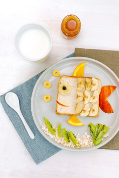 Naklejki Funny cute sandwich toast bread.Kids childrens baby's dessert healthy breakfast lunch food art like fish with fruits,wooden background close up,top view