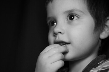 Young boy with curious expression explores thoughts in black and white setting