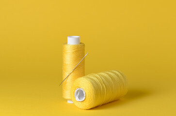 Yellow thread spools with needle, still life background with copy space for text